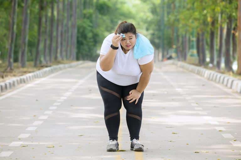 A fat runner taking a break to sweat and catch her breath. Boob sweat is a problem for overweight runners