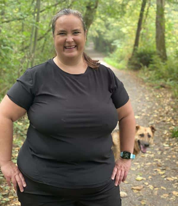 A fat runner posing on a hiking trail with the cutest German Shepherd photobombing in the background